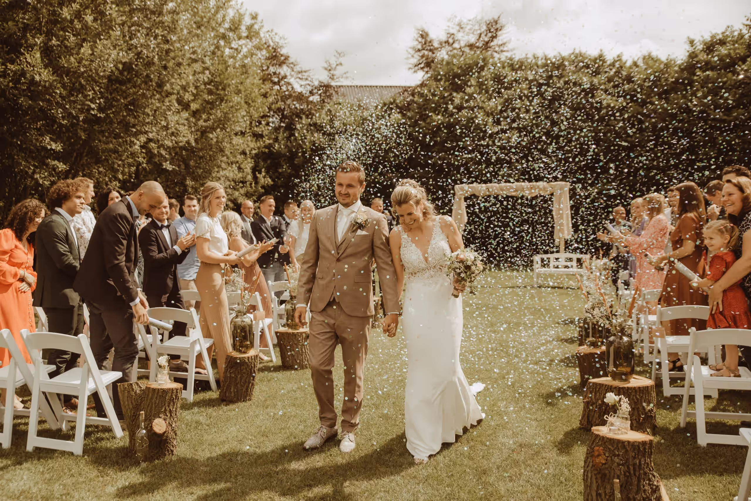 Pasgetrouwd stel loopt hand in hand door een regen van confetti